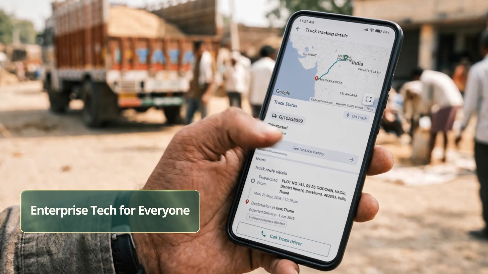 A hand holding a phone showing Truck tracking details with a route map, status On Track and route details, with a loaded truck in the background.